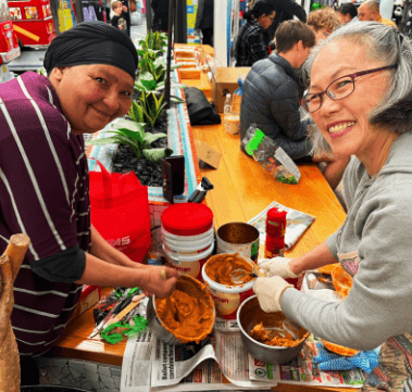 Two volunteers preparing sandwich spread together.